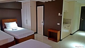 A hotel room with two beds, a wardrobe, a small table, and a kitchenette. - Palawan Palm Suites (Puerto Princesa)