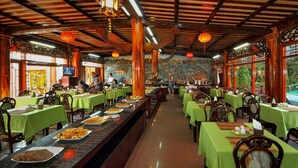 A restaurant with green tablecloths, wooden chairs, and a buffet line. - Thanh Binh II (Da Nang)