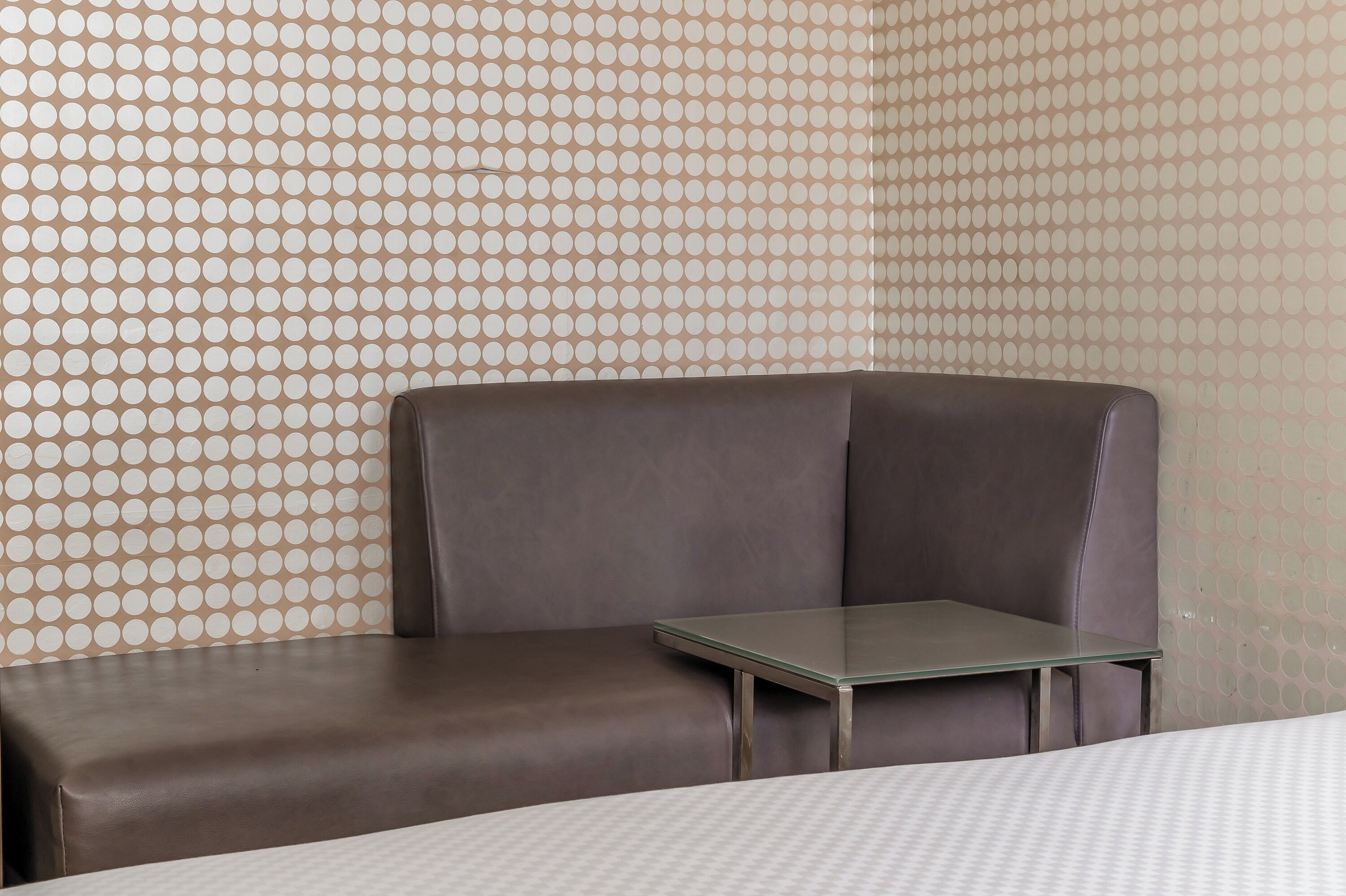 A corner seating area with a glass table and a patterned wall.