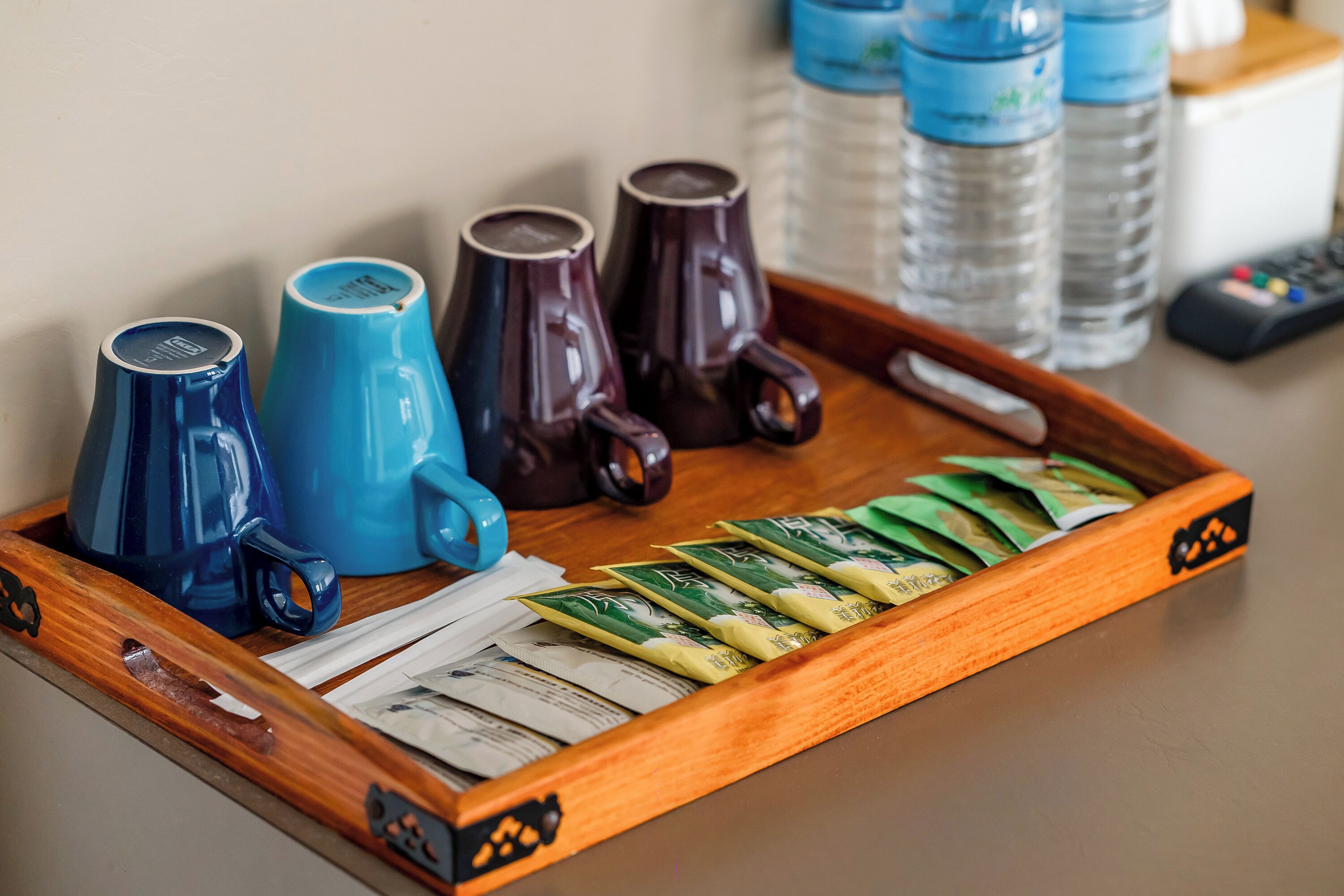 Uma bandeja com xícaras de café, chá e sachês de chá sobre uma mesa de madeira.