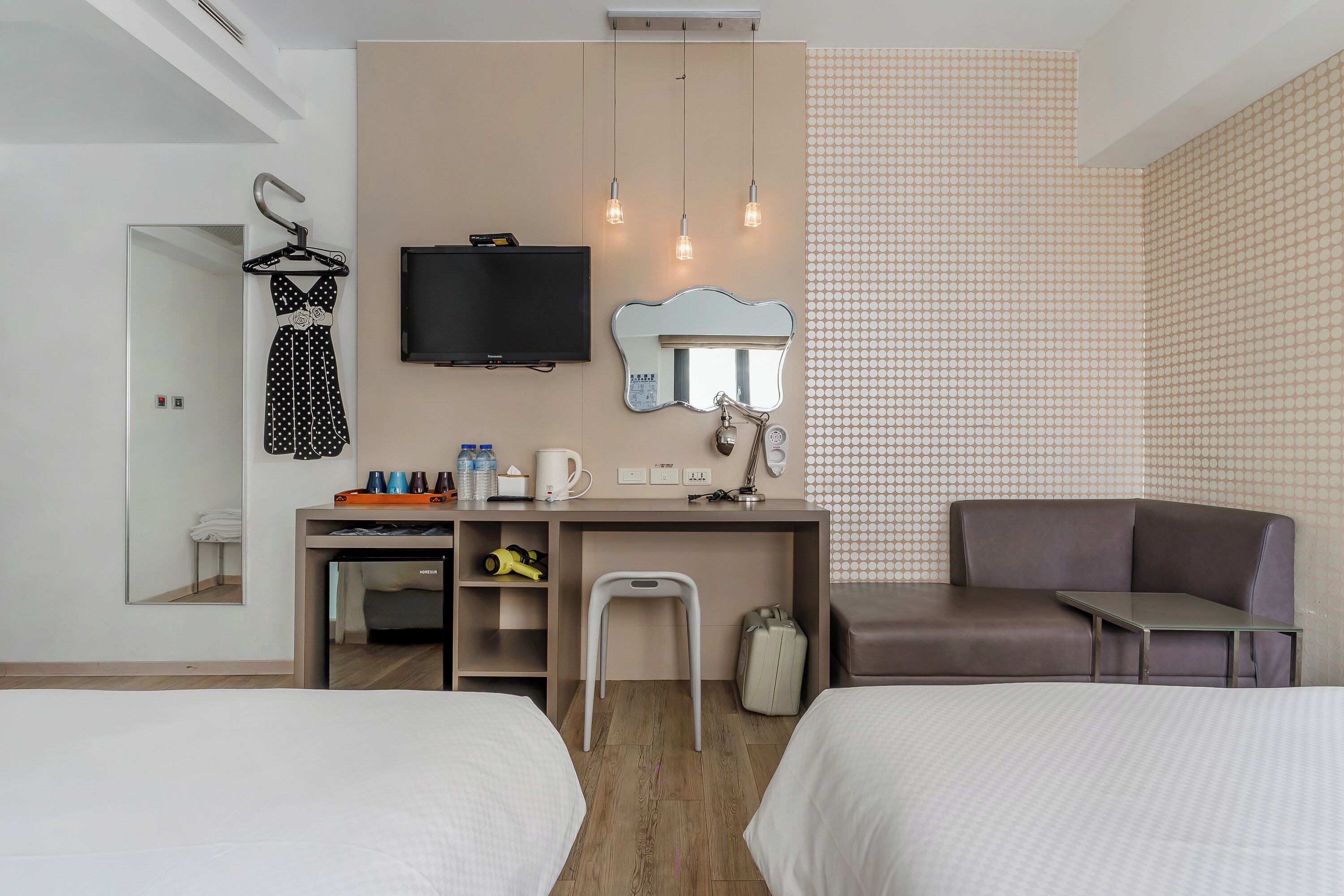 Quarto de hotel com duas camas, uma mesa de trabalho com espelho, televisão e área de estar.
