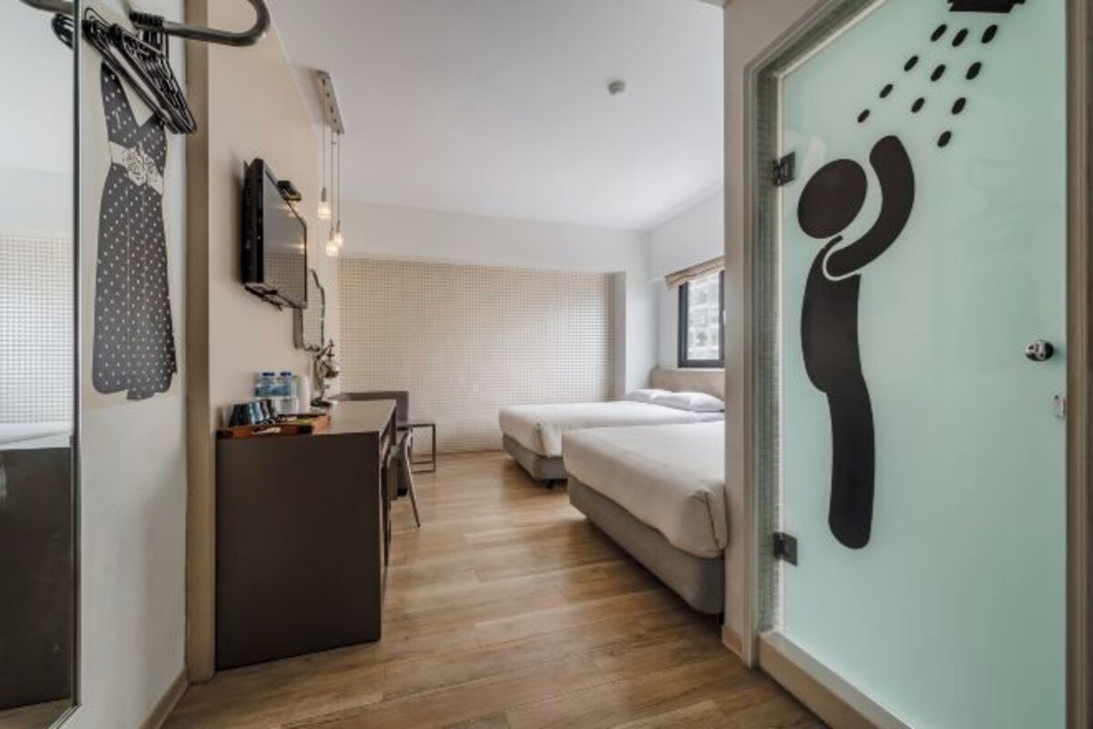 A compact hotel room with a kitchenette, a bed, and a shower area.