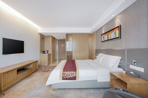 Une chambre d’hôtel moderne dotée d’un grand lit, d’un téléviseur à écran plat, d’une table de chevet et d’un bureau avec une chaise.
