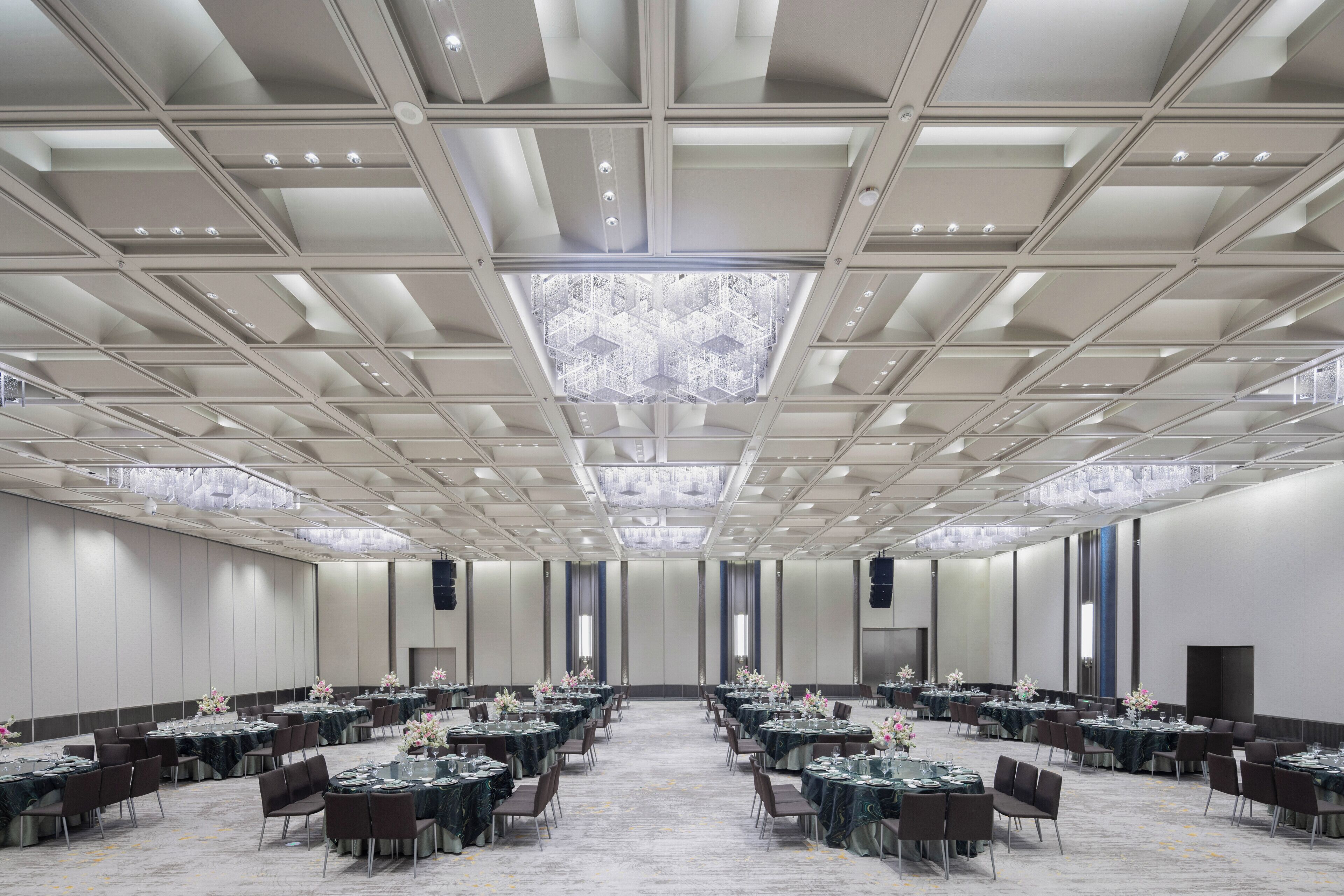 A large conference room with tables and chairs, a patterned ceiling, and a carpeted floor.