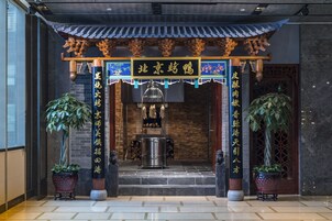 Una entrada de arquitectura china tradicional con tejado de baldosas, pilares de madera y plantas en macetas.
