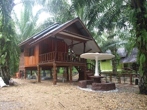 A wooden cabin with a balcony, surrounded by dense tropical foliage.
