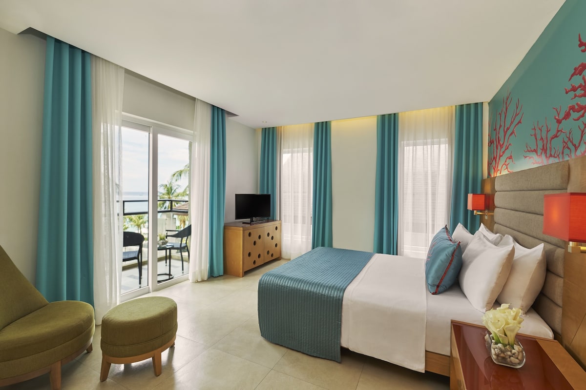 Een hotelkamer met een bed, een televisie, een bureau en uitzicht op de omgeving.