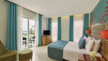 A hotel room with a bed, a TV, a desk, and a view of the outdoors.