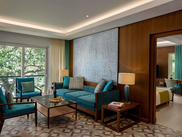 Una habitación de hotel con sofá, sillones, una mesa de centro y cama.