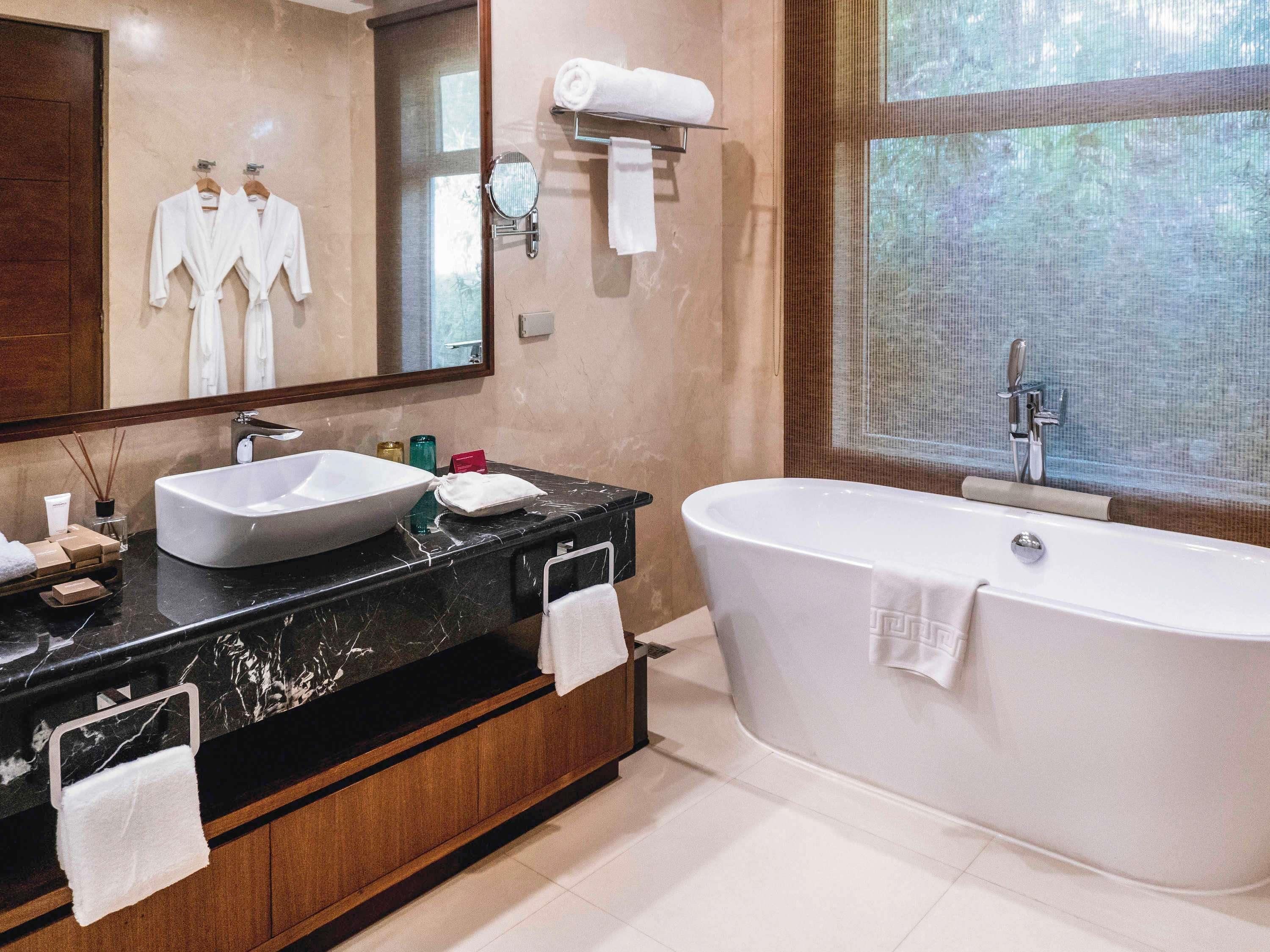A modern bathroom with a large bathtub, a vanity with a large sink, and a mirror above the sink.