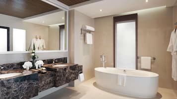 Un baño moderno con una bañera independiente, un espejo grande y un tocador de mármol.