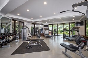 Een moderne sportschool met diverse trainingsapparaten, grote ramen en een ruimtelijk, schoon ontwerp.