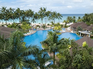 Relax by the resort's central pool surrounded by palm trees and ocean views.