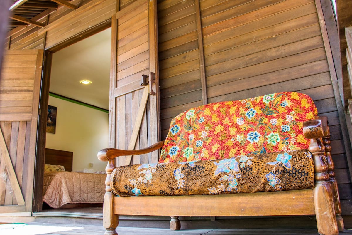 A wooden bench with a colorful floral cushion outside a rustic building.
