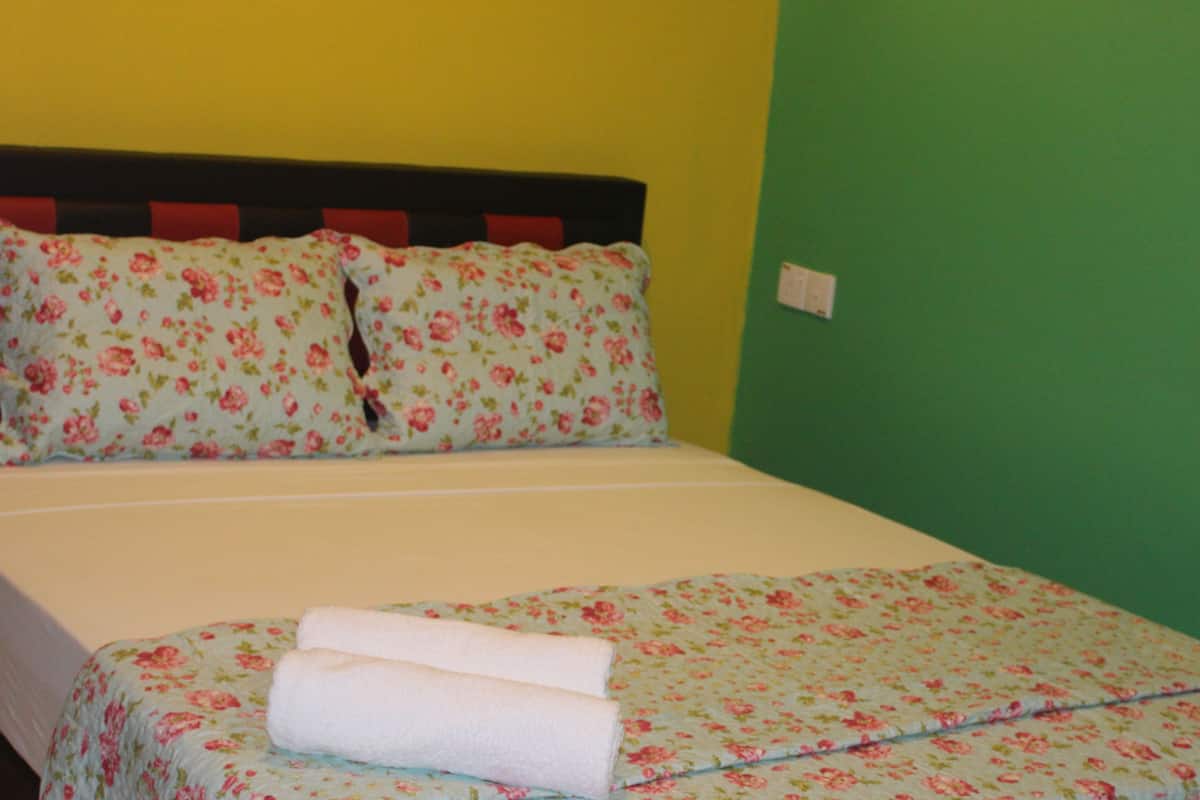 A bed with floral bedding, two pillows, and two rolled towels.