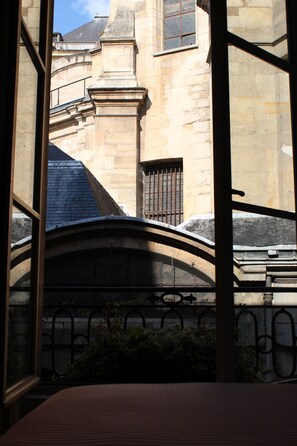 Vista a través de una ventana que muestra un edificio con paredes de piedra, un portón metálico y una estructura curva.
