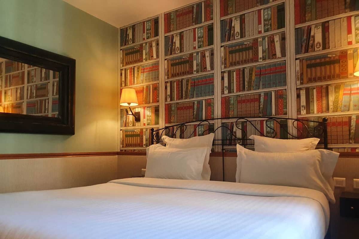Una cama bien hecha en una habitación con una amplia estantería llena de libros.