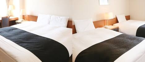 A hotel room with a large bed, two bedside tables, a lamp, a picture on the wall, and an air conditioning unit.