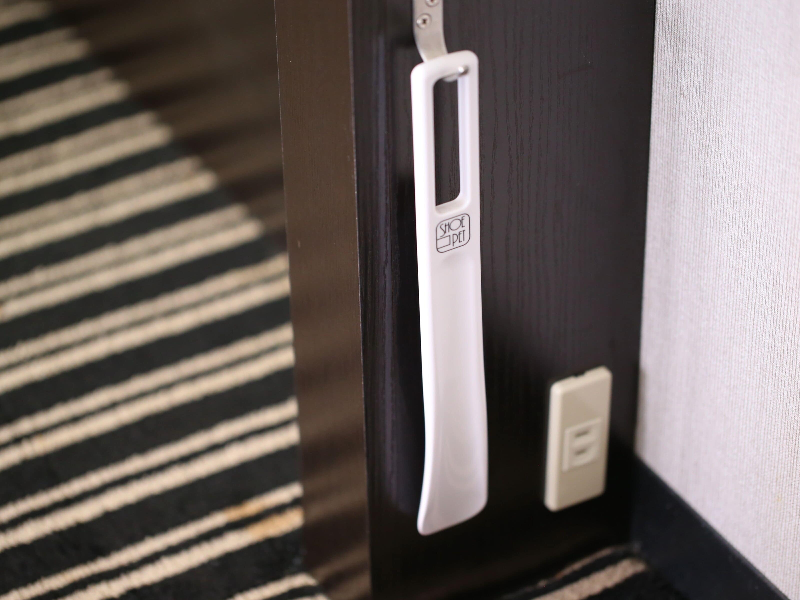 A door with a white handle and a shoe pet logo, a power outlet, and a striped carpet.