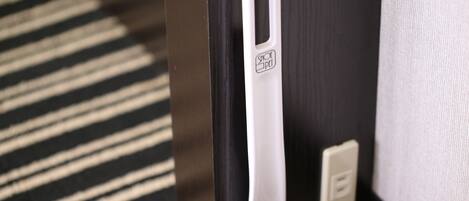 A door with a white handle and a shoe pet logo, a power outlet, and a striped carpet.