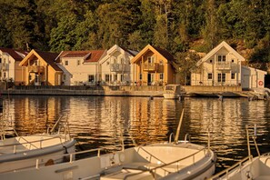 A waterfront property with multiple houses, a dock with boats, and a forested hillside in the background.