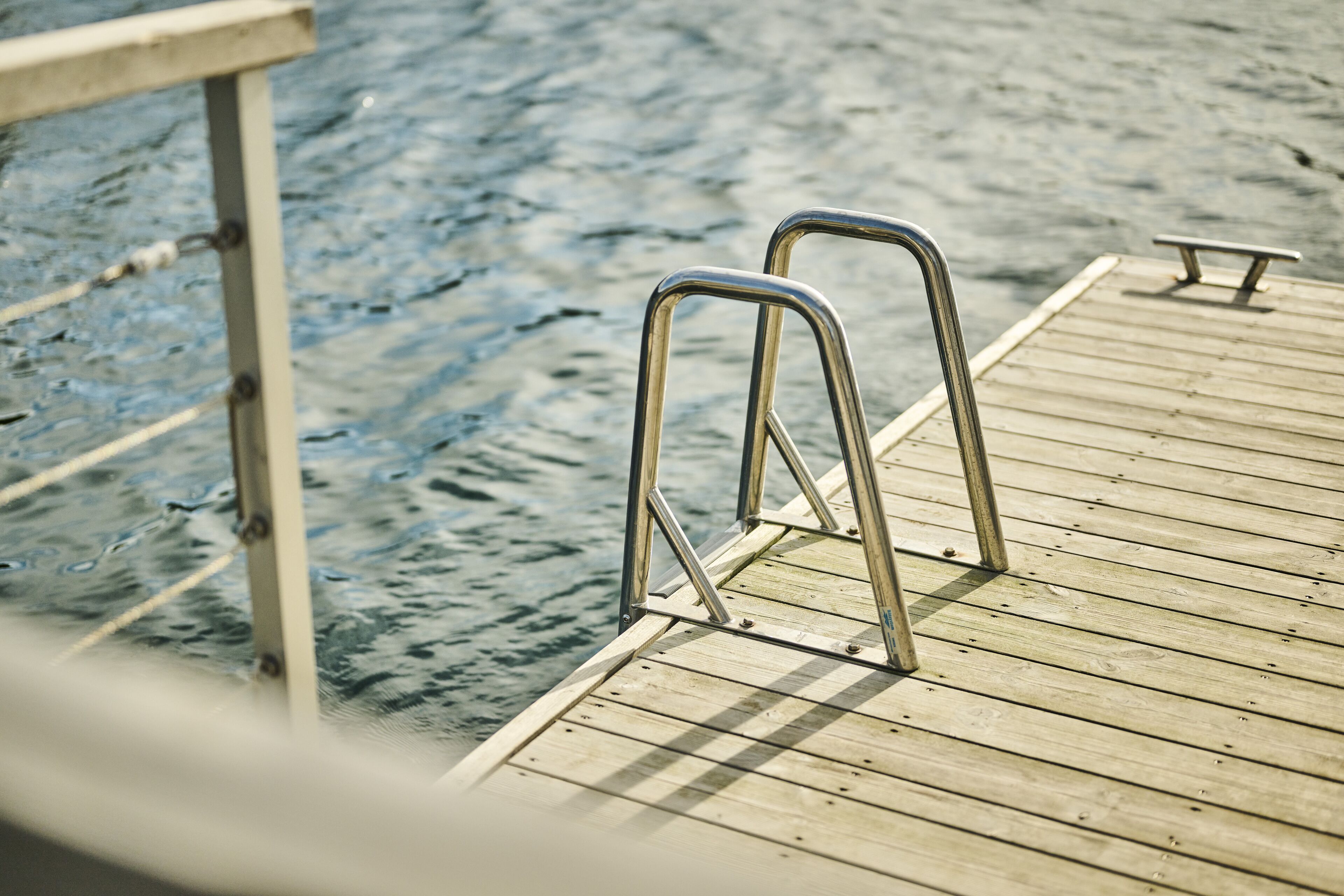 Une jetée en bois, dotée de garde-corps métalliques qui s’étendent au-dessus de l’eau.