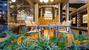 A modern interior with a glass wall, a table with chairs, and potted plants. - Days Inn by Wyndham Patong Beach Phuket (Patong)