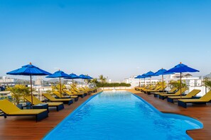 Una piscina al aire libre, sombrillas, sillones reclinables de piscina