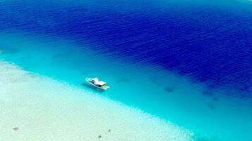 A boat on a turquoise sea with clear waters and a sandy beach.