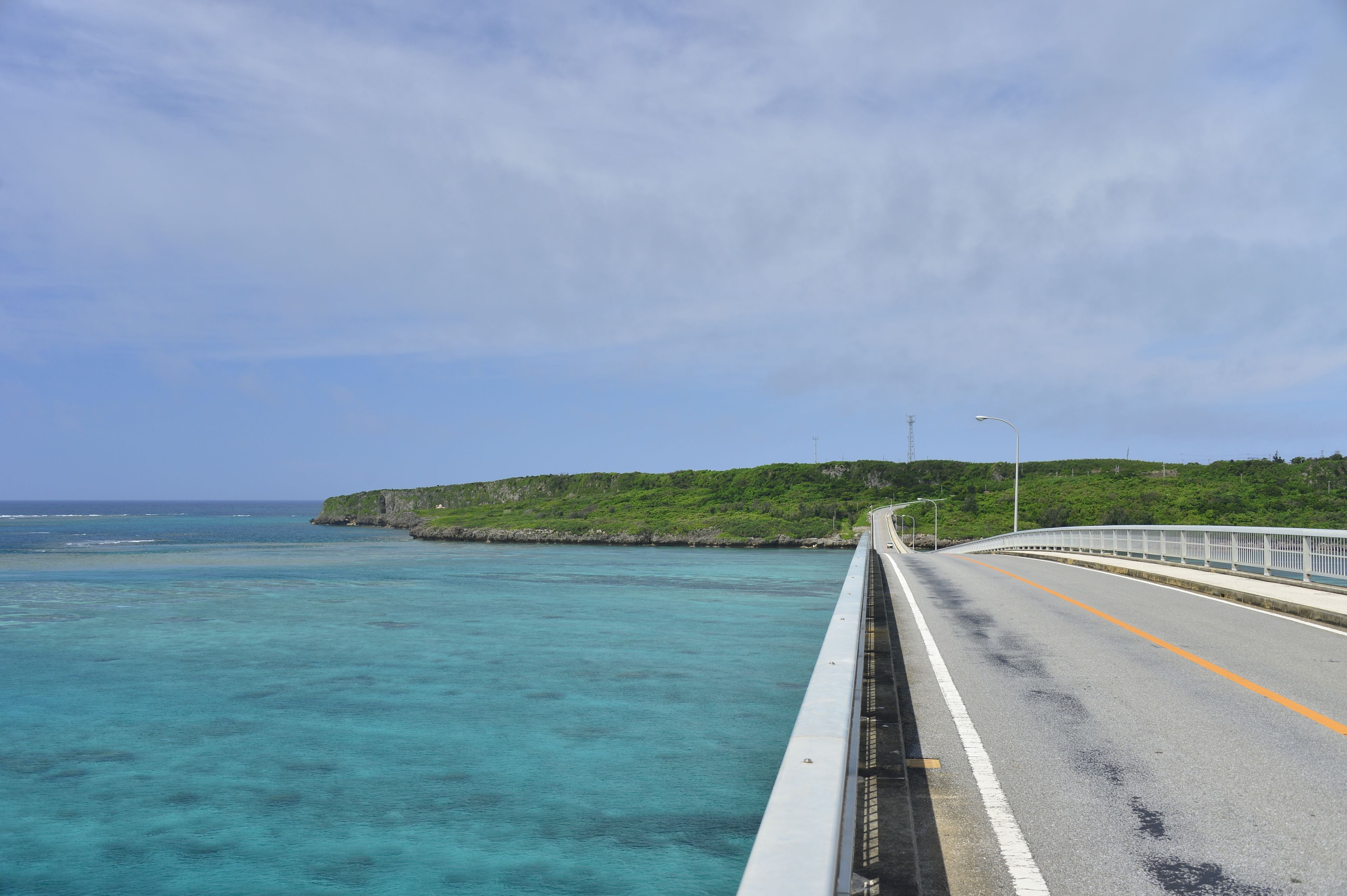 A coastal road with a guardrail and a view of the ocean.