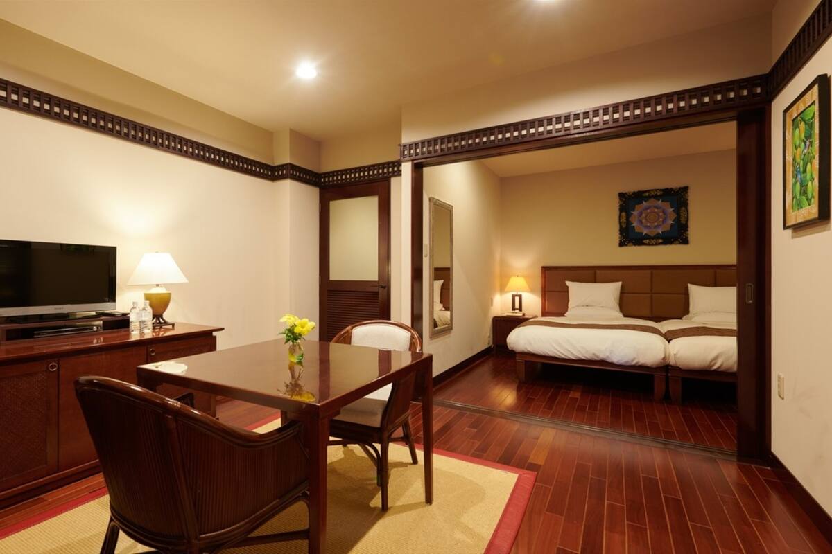A hotel room with a dining area, a TV, a bed, and a bathroom visible through an open door.