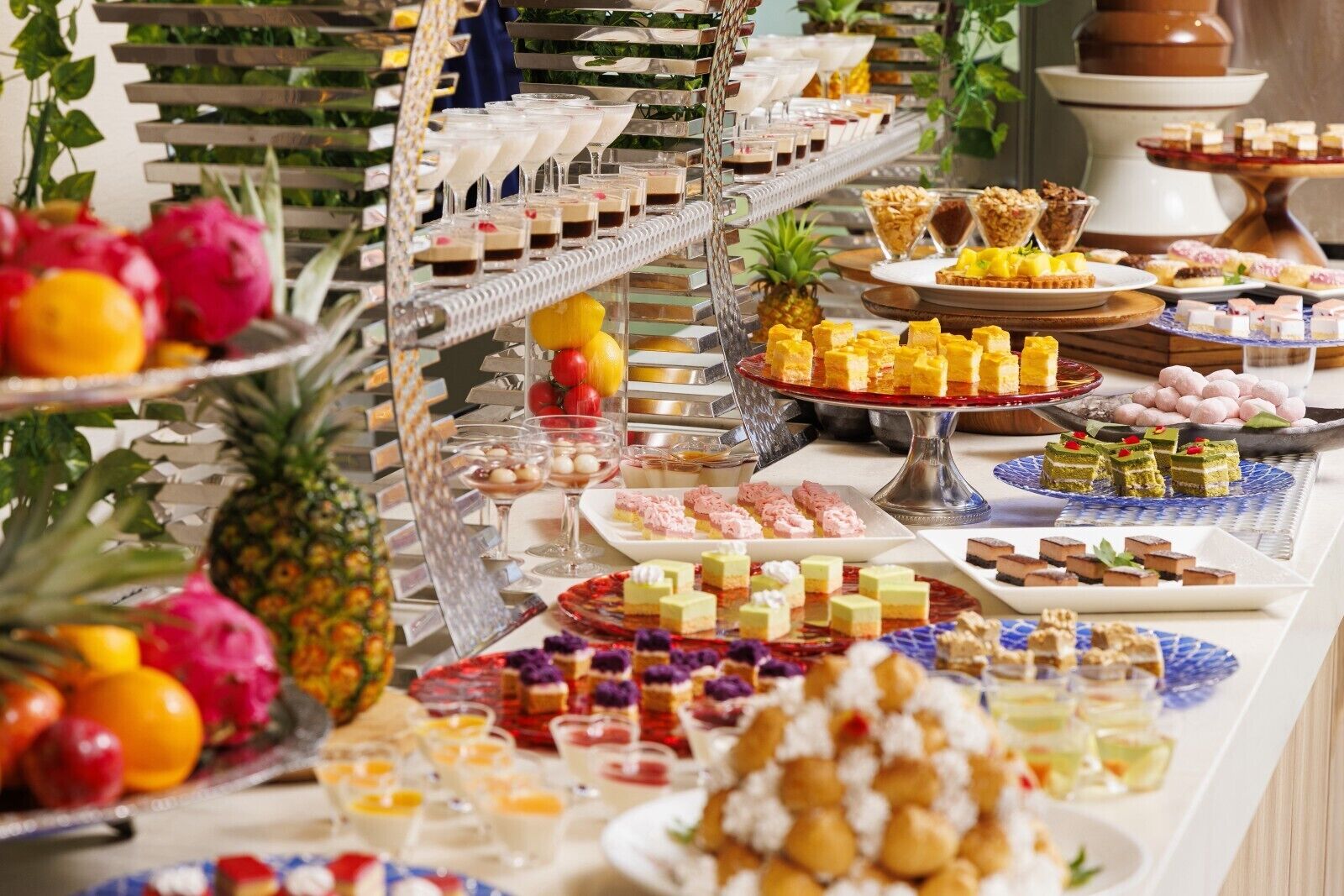 A buffet with various desserts, fruits, and beverages.