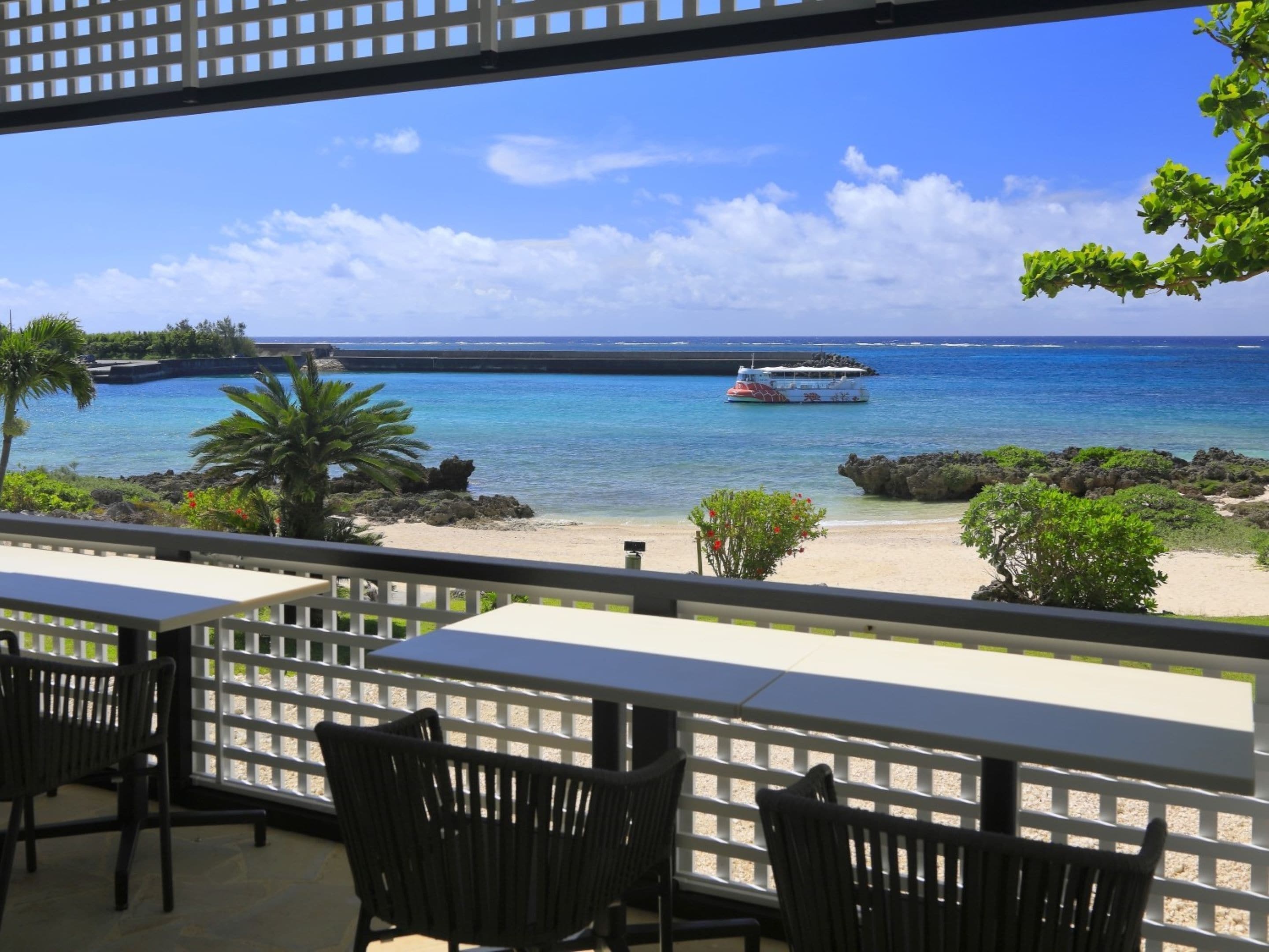 Vista al mar desde un balcón con mesa y sillas, con vista a la playa y el océano.