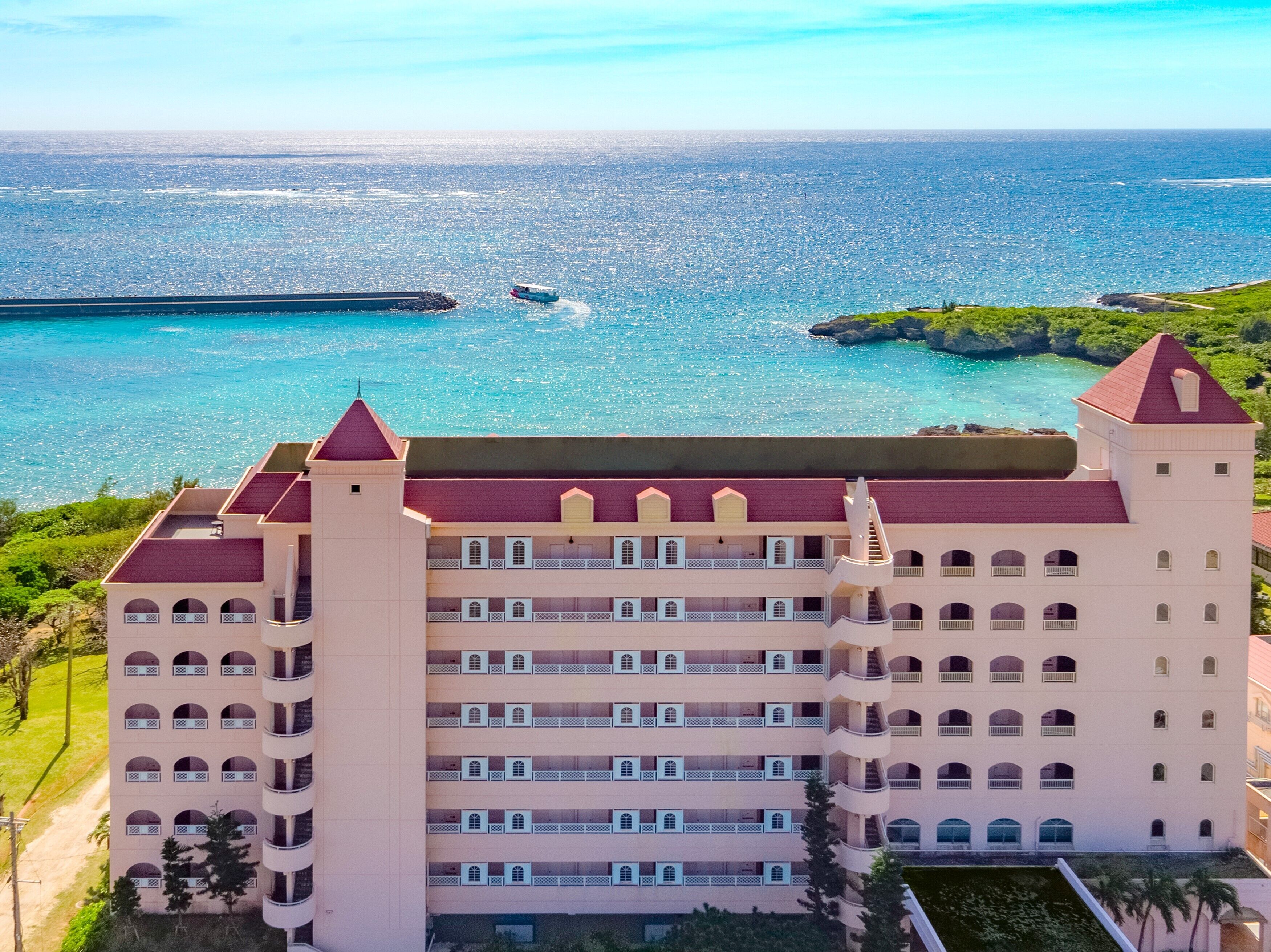 Een groot, meerhoog hotel met een centrale binnenplaats, nabij een waterlichaam met een pier.