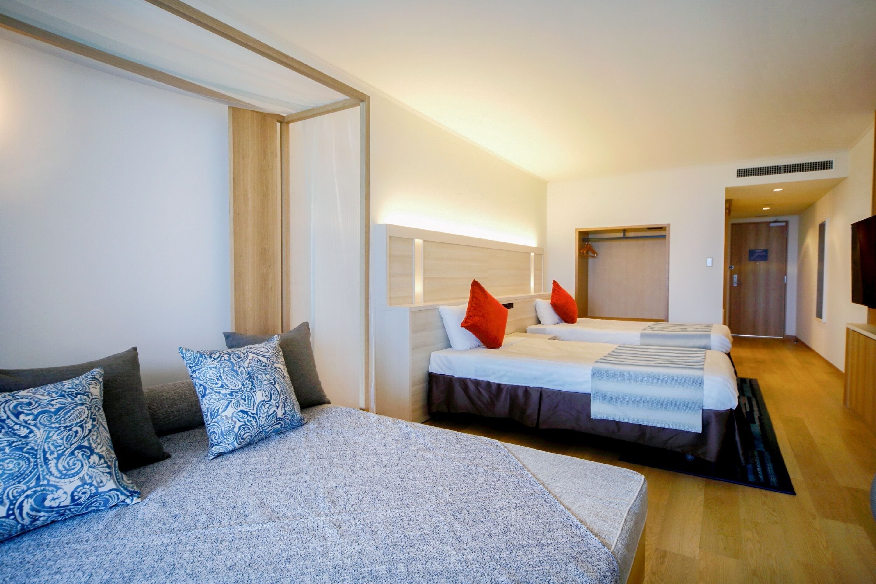 A modern hotel room with a large bed, a sofa, and a TV.