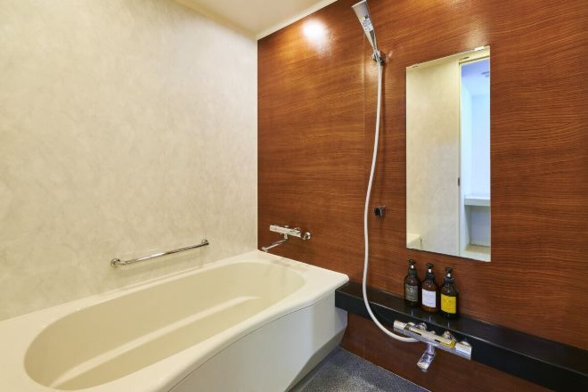 Un baño moderno con bañera, tocador de madera, espejo y ducha.