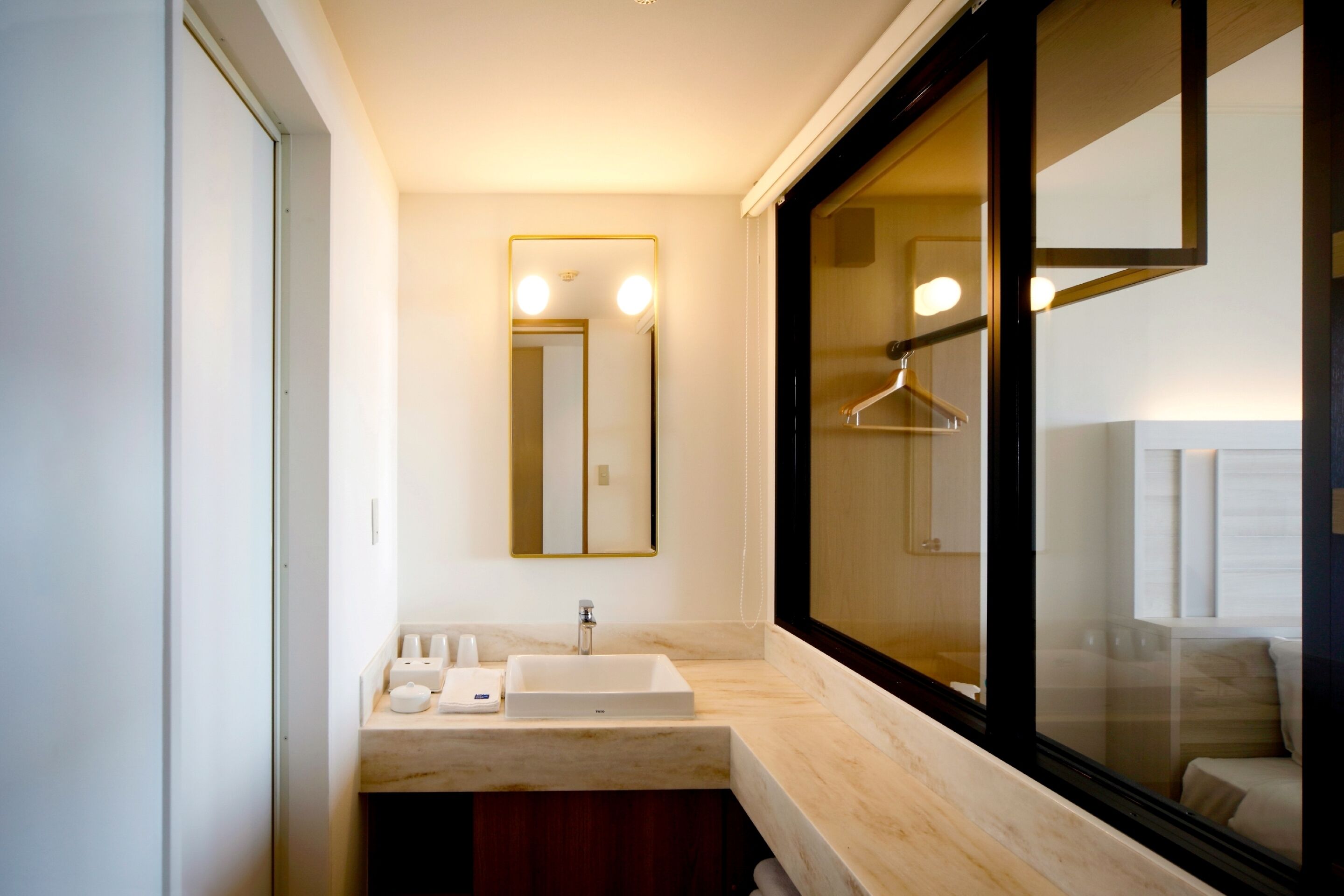 A modern bathroom with a large mirror, two sinks, and a window.