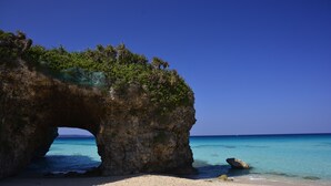Une formation rocheuse naturelle dotée d’une ouverture en forme de tunnel qui mène à une eau turquoise et cristalline.