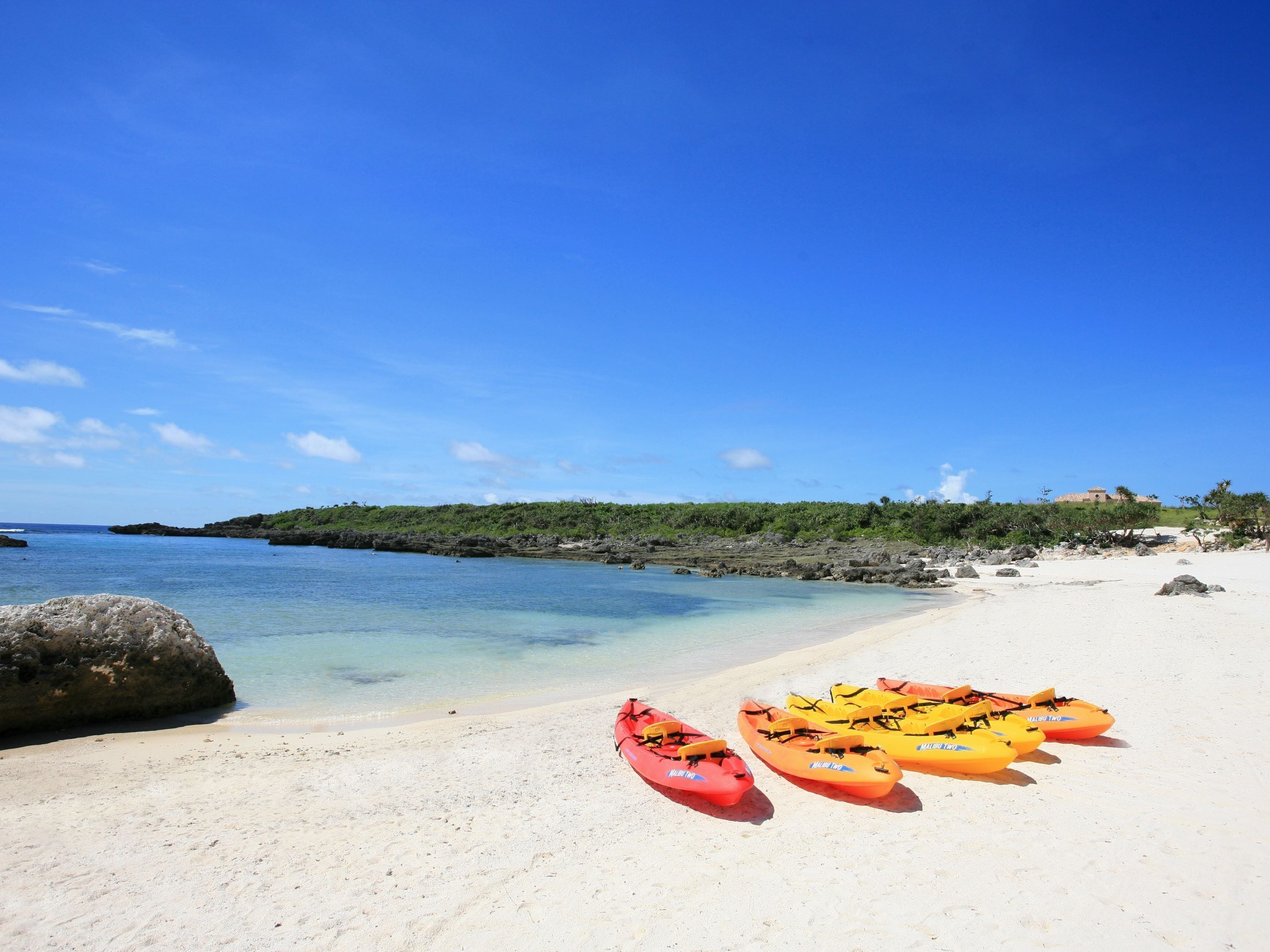 Una playa con kayaks bajo un cielo azul despejado.