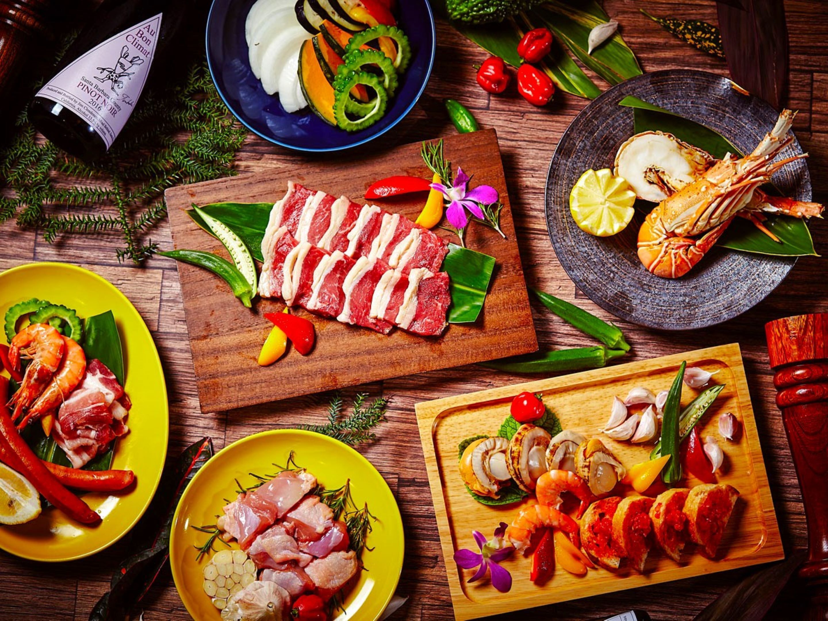 A variety of seafood dishes, including shrimp, crab, and sliced meats, arranged on wooden boards and plates.