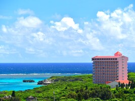 Un hotel con varios balcones con vistas a la costa y aguas azul turquesa, con vista al océano.