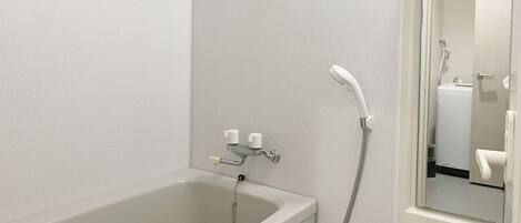 A bathroom with a bathtub, a shower, and a mirror. There are bottles of hand soap on a shelf above the mirror.