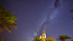 Una iglesia con un campanario bajo un cielo nocturno estrellado.