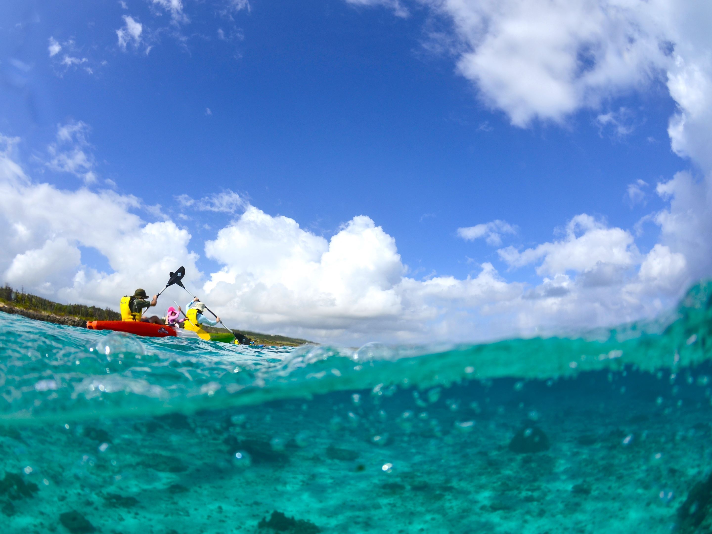 A kayak on a turquoise sea with a clear sky and clouds.