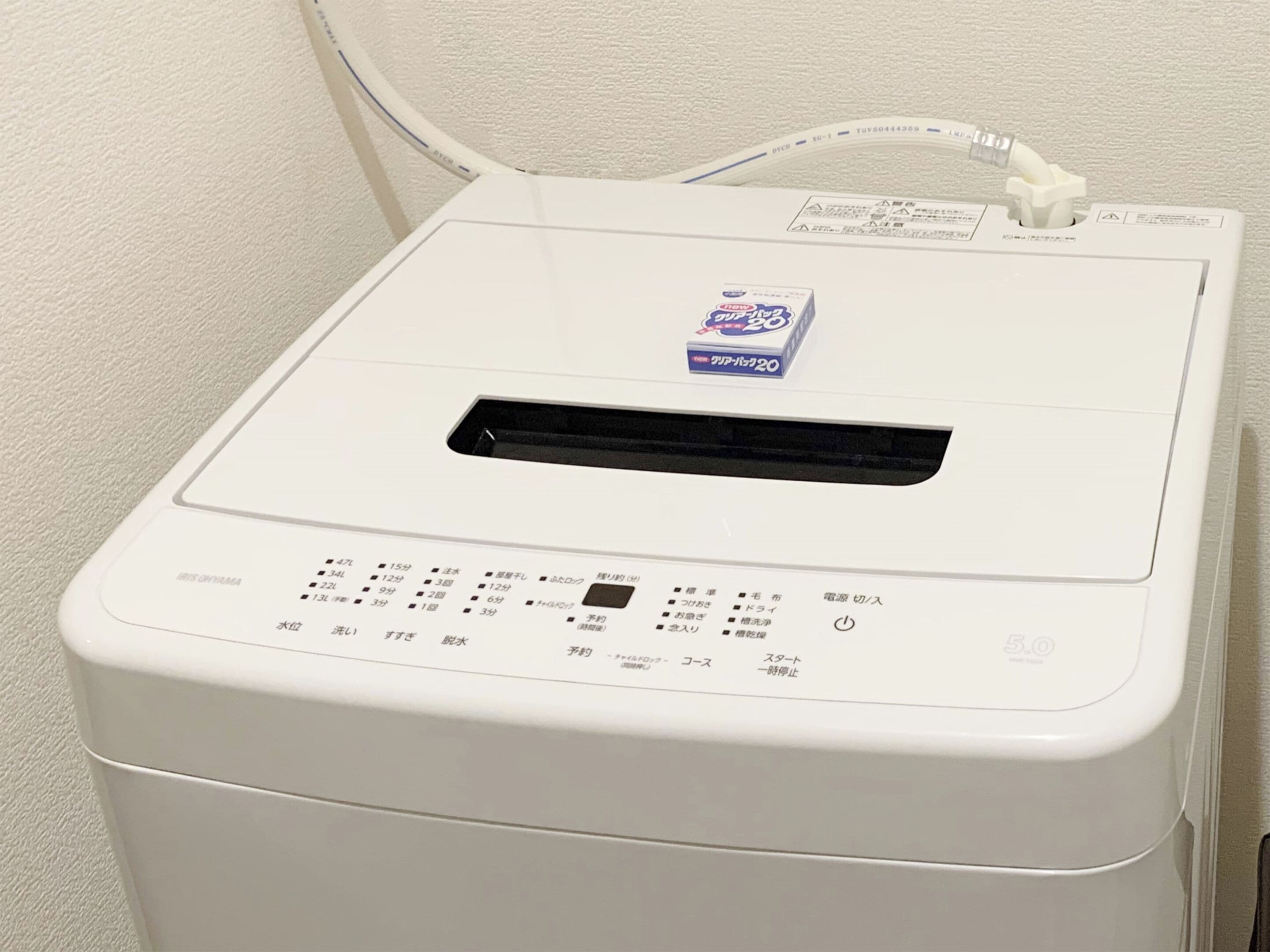 A white, compact, front-loading washing machine with a control panel and a power cord.