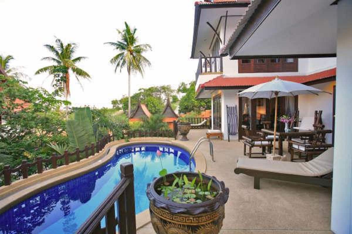 A pool area with a wooden deck, lounge chairs, and a large decorative pot.