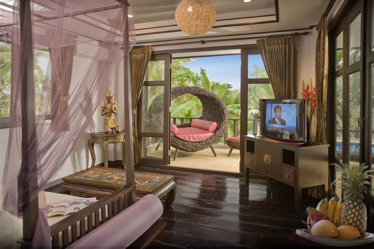 A room with a bed, a television, a wicker chair, and a view of the outdoors.
