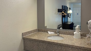 A bathroom with a granite countertop, a sink, a mirror, and a hairdryer.