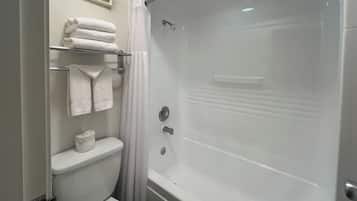A bathroom with a toilet, a shower with a glass door, and a towel rack with folded towels.