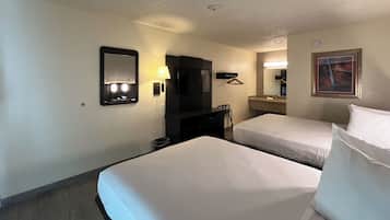 Habitación de hotel con dos camas, un escritorio, un televisor y un espejo de baño.